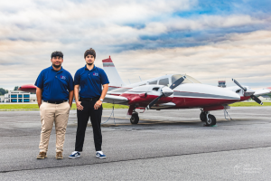 two males standing in front of a piper seneca airplane on an airport ramp in Georgia