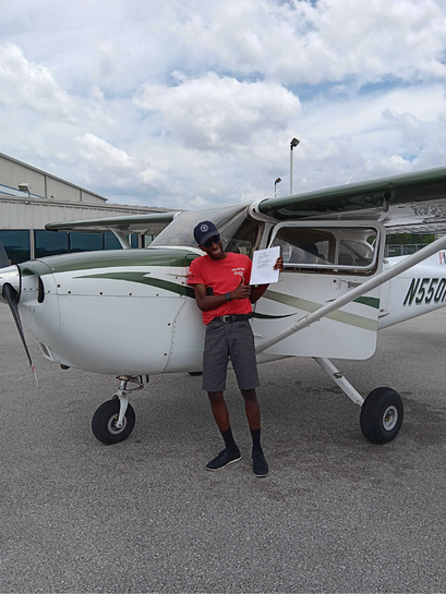 Student smiling and standing in front of Cessna 172 N550ND with pilot certificate